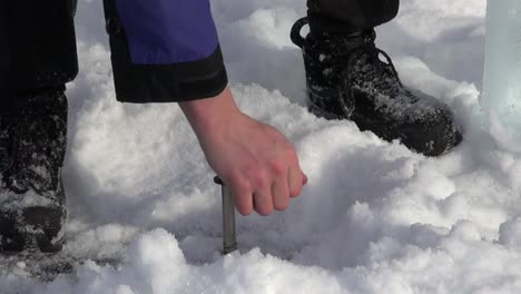 Installing-ice-screw-in-frozen-lake-surface