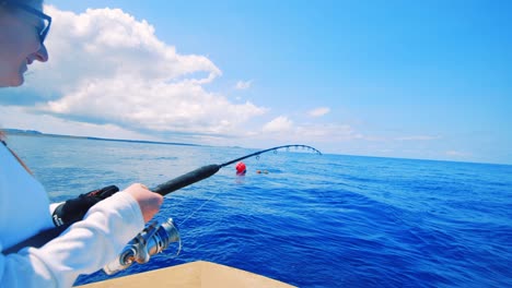 Happy-young-woman-reeling-in-fish-in-bright-blue-Caribbean-Sea,-Slow-Motion