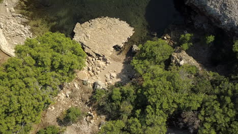 Aerial-birds-eye-view-of-a-small-lake-surrounded-by-trees-and-ancient-ruins