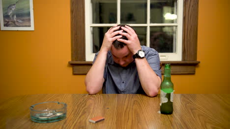 Stressed-out-male-at-table-drinking,-running-hands-through-hair