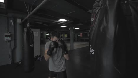 Young-athletic-man-doing-exercise-at-the-gym-with-a-punching-bag