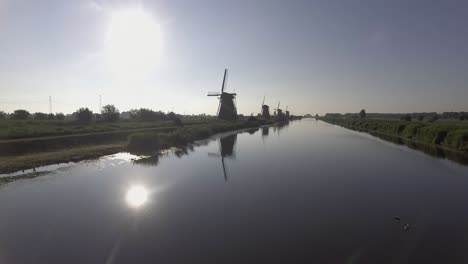 A-drone-shot-panning-forward,-around-Dutch-Windmills-during-sunrise