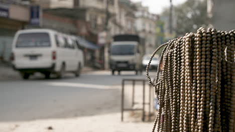 Nepalesische-Perlenketten-Im-Fokus,-Verkehr-Und-Passanten-Im-Hintergrund-Unscharf