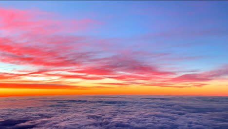 Dramatic-golden-sunrise-with-beautiful-colored-clouds-as-seen-from-the-aircraft-flying-above-overcast-clouds