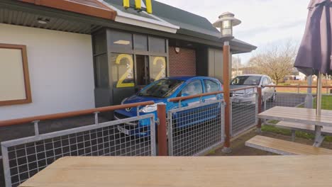 People-paying-at-the-McDonalds-drive-through,-thru-at-the-famous-Golden-Arches-restaurant,-now-open-24-7-serving-fast-food-in-the-city-centre