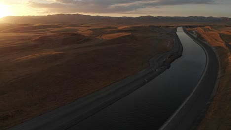 Luftaufnahme-Von-Links-Nach-Rechts-Bei-Sonnenuntergang-über-Dem-Aquädukt,-Das-Kalifornische-Bauernhöfe-Und-Menschen-Mit-Frischwasser-Versorgt