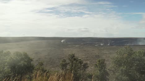 Right-to-left-pan-of-volcano-crater-with-heavy-amounts-of-steam-and-smoke-coming-out-of-the-ground-and-covering-forest