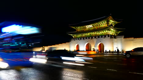 Circa---Night-time-lapse-of-busy-traffic-passing-in-front-of-Gyeongbokgung-Palace-in-South-Korea,-illuminated-oriental-building