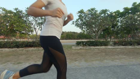 A-slowmotion-side-shot-of-a-young-thai-girl-jogging-through-a-park