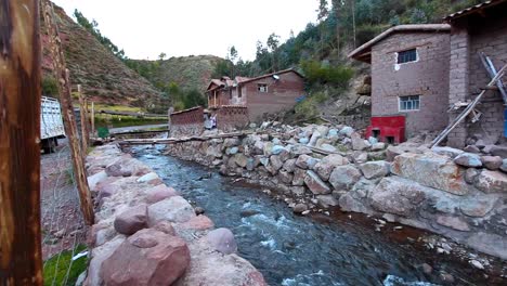 A-shot-of-a-house-on-the-side-of-a-stream-near-a-few-small-adobe-houses-in-Peru