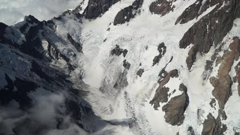 Hooker-glacier,-Southern-Alps,-New-Zealand-with-clouds,-snow-and-rocky-mountains-from-scenic-airplane-flight