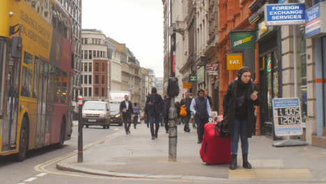 Young-female-tourist-struggling-with-luggage-on-a-busy-London-street