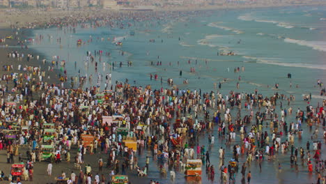 Aerial-view-over-the-sea-view-beach-at-Karachi-Pakistan,-Hundreds-of-people-are-together-to-enjoy-beautiful-blue-sea