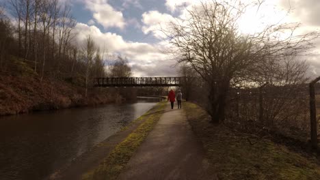 2-women-take-a-walk-along-by-the-former-industrial-canal-in-Stoke-on-Trent,-a-poverty-stricken-area-featuring-many-factories-in-ruins-along-by-the-canal