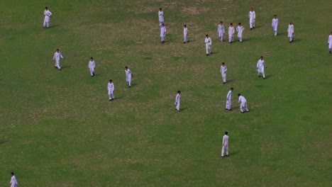Peshawar,-Pakistan,-students-playing-foot-ball-aerial-view-from-the-trees,-Students-are-in-white-shalwar-kameez-uniforms,-grass-in-the-ground
