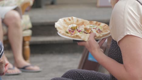 Woman-eating-and-enjoying-Tasty-Flatbread-Outside