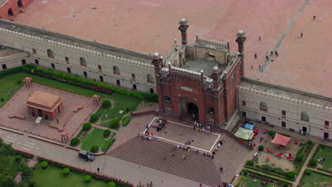 Lahore,-Pakistan,-Zooming-in-aerial-view-of-the-entrance-of-the-Badshahi-Mosque,-Visitors-ladies,-gents-and-children-sat-the-stairs-of-the-Mosque,-People-entering-in-the-Mosque