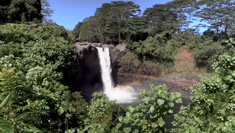Rainbow-at-the-bottom-of-Rainbow-falls-with-large-amount-of-water-flowing-and-visitors-walking-on-the-observation-deck