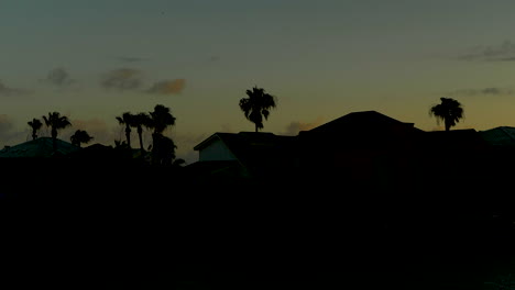 Sunset-off-the-Texas-coast-behind-silhouetted-houses-and-trees