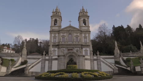 Weitwinkelaufnahme-Der-Kirche-Von-Bom-Jesus-In-Braga,-Portugal,-Mit-Ziehenden-Wolken-Im-Hintergrund-Und-Einem-Blumenarrangement-Im-Vordergrund