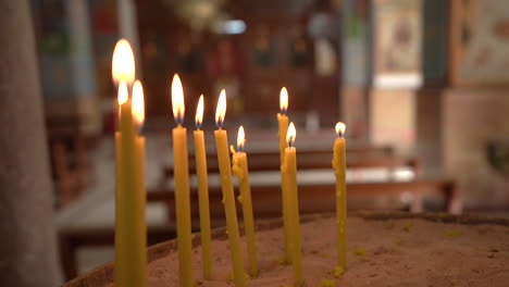 Burning-Candle-Sticks-With-Pieces-of-Wax-At-the-Bottom-of-Sand-Bowl-inside-Madaba-St-George's-Greek-Orthodox-Church,-100-Frames-Per-Second