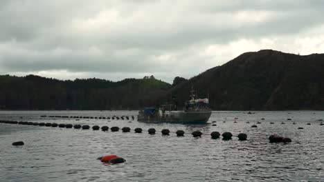 SLOWMO---Mussel-and-oyster-boat-harvesting-at-mussel-farm-in-Marlborough-Sounds,-New-Zealand