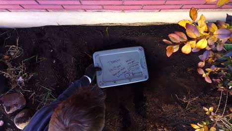 Digging-and-measuring-a-dead-house-pet’s-grave-and-hole-in-a-flower-garden