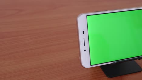 Slide-motion-of-The-green-screen-phone-is-placed-on-a-pedestal-on-a-wooden-table