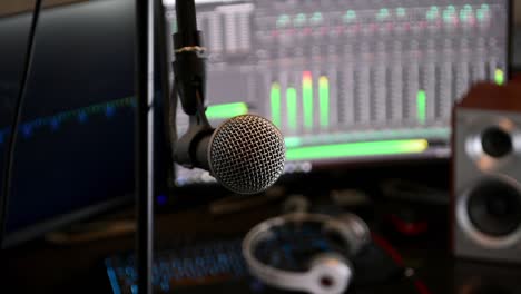 Locked-off-shot-of-a-microphone-in-close-up,-with-computer-monitors-in-the-background