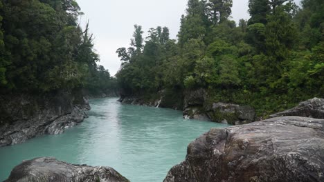 SLOWMO---Glacier-river-flows-through-native-lush-New-Zealand-forest,-Hokitika-Gorge,-South-Island