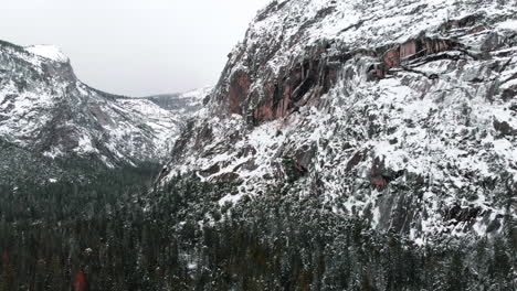 Aerial-drone-footage-flying-over-Yosemite-valley-blanketed-in-snow,-surrounded-by-granite-cliffs-in-winter