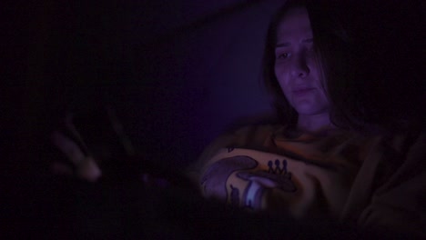 A-woman-playing-with-her-phone-in-bed-in-the-night-with-screen-reflection-on-her-face