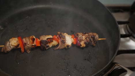 Meat-and-vegetable-skewer-cooked-on-a-black-pan-in-peanut-oil