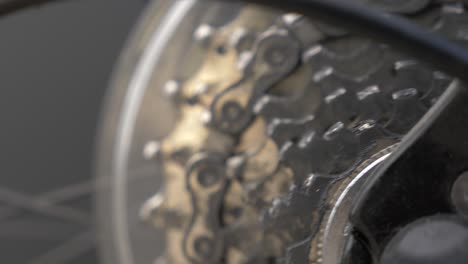 Slow-motion-zoom-into-moving-bicycle-wheel-and-gear-chain-cogs,-low-depth-of-field
