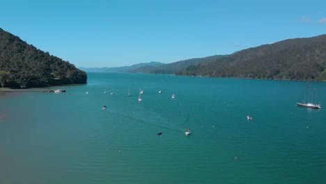 SLOWMO---Aerial-shot-of-sail-boats-by-Anakiwa-in-Queen-Charlotte-Sound,-Marlborough-Sounds,-South-Island,-New-Zealand