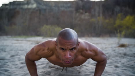 Attractive-and-athletic-man-doing-push-ups-on-a-beach-in-slow-motion