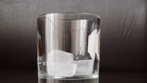 Eiswürfel-In-Ein-Leeres-Whiskyglas-Geben