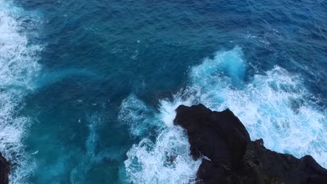 Aerial-view---Blue-water-waves-crashing-against-rocks-in-Hawaii