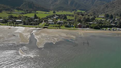 Slowmo---Flug-über-Meerwasser-Mit-Der-Stadt-Anakiwa-Im-Hintergrund,-Queen-Charlotte-Sound,-Marlborough-Sounds,-Südinsel,-Neuseeland---Luftaufnahme