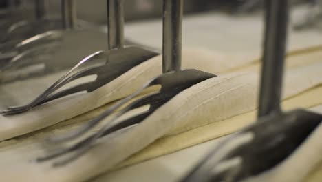 time-lapse-of-folding-raw-pastry-dough-automatically-by-industrial-automated-machine-inside-a-bread-factory