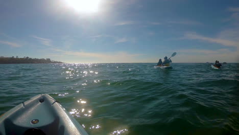 A-group-of-kayakers-rowing-towards-the-sun-in-the-middle-of-the-sea-at-San-Diego