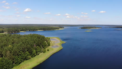AERIAL:-Slow-Flight-Above-the-Blue-Lake-Towards-the-Horizon-Filled-with-Green-Forests