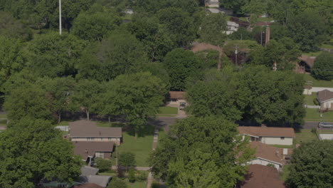 Aerial-pull-away-over-suburban-neighborhood-with-streets,-houses-trees-and-power-lines