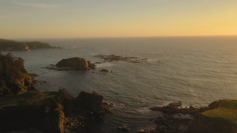 Drohne-Fliegt-Rückwärts-über-Wunderschöne-Felsnadeln-Und-Zeigt-Rechts-Den-Leuchtturm-Von-Cape-Arago