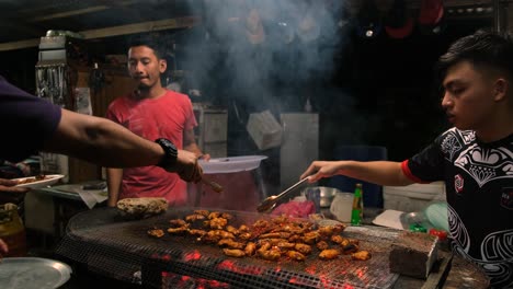 View-of-3-Malaysia-Men-Barbecuing-tasty-chicken-wings-at-a-BBQ-Grill-at-night
