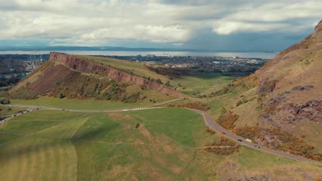 Drone-shot-of-cars-driving-around-holyrood-park