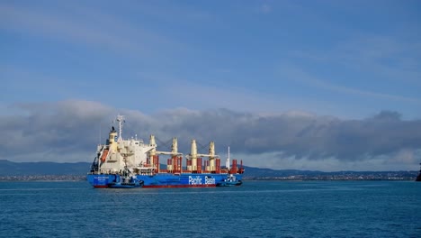 Weitwinkelaufnahme-Eines-Frachtschiffs,-Das-Zur-Chelsea-Zuckerfabrik-Im-Hafen-Von-Auckland-Fährt,-Mit-West-Auckland-Als-Hintergrund