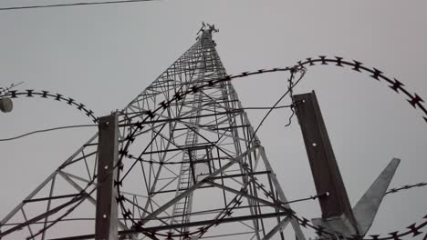 Low-angle-razor-wire-looking-up-at-cell-towers