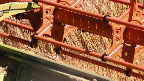 Combine-harvester-reaping-harvest-in-a-field-of-wheat-slow-motion-close-up-view-daylight-scene