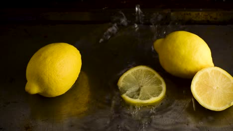 Gruppe-Ganzer-Zitronen-Mit-Von-Oben-Fallengelassenen-Scheiben,-Die-In-Dunkler-Umgebung-Im-Wasser-Spritzen
